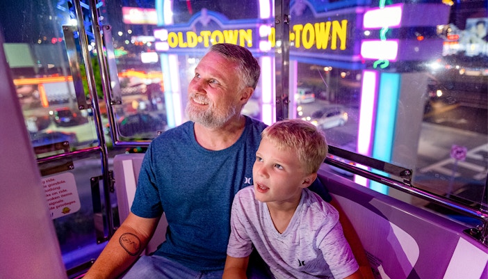 Guests enjoying a ride at Old Town, Orlando with neon lights in the background.