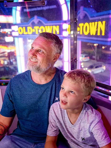 Guests enjoying a ride at Old Town, Orlando with neon lights in the background.