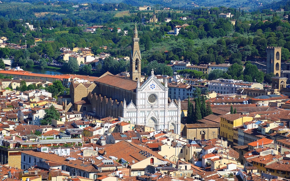 Aerial view of Santa Croce Basilica in Florence, Italy, surrounded by cityscape and greenery.