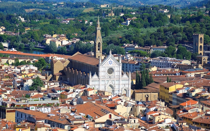 Aerial view of Santa Croce Basilica in Florence, Italy, surrounded by cityscape and greenery.