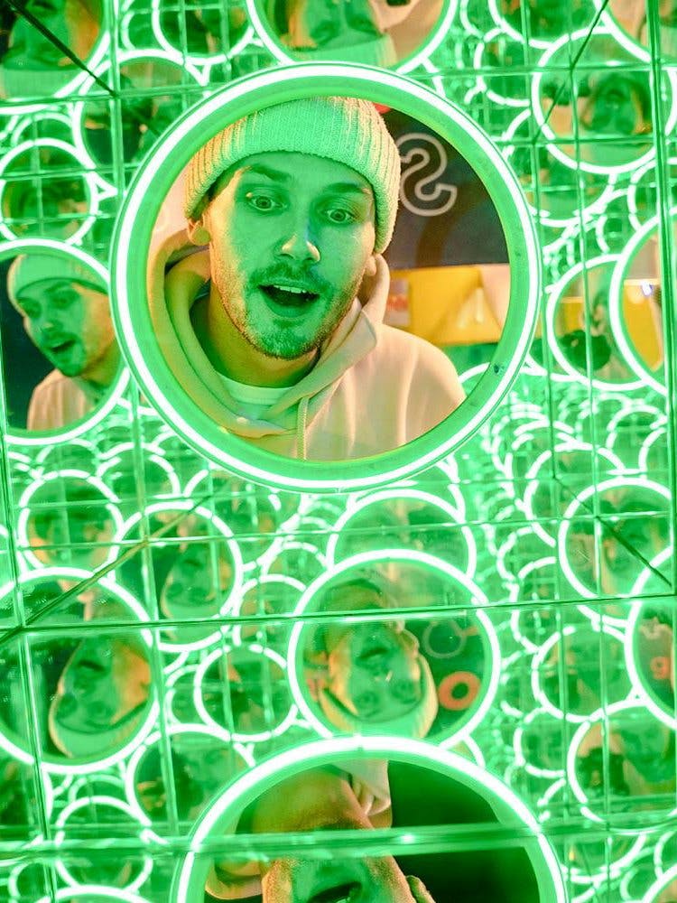 Man exploring mirror maze at World of Illusion exhibit.