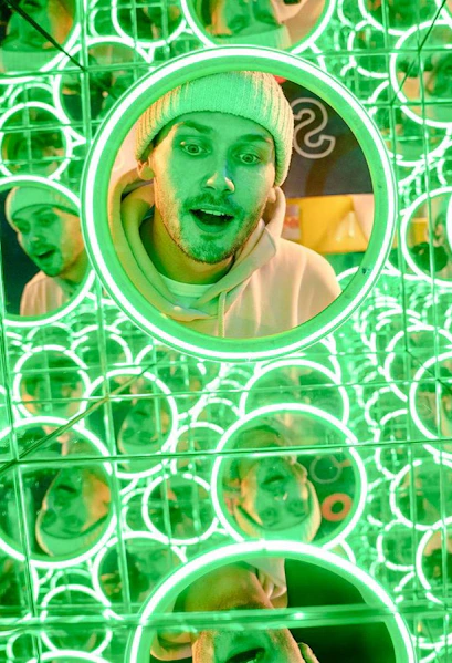 Man exploring mirror maze at World of Illusion exhibit.