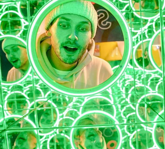 Man exploring mirror maze at World of Illusion exhibit.