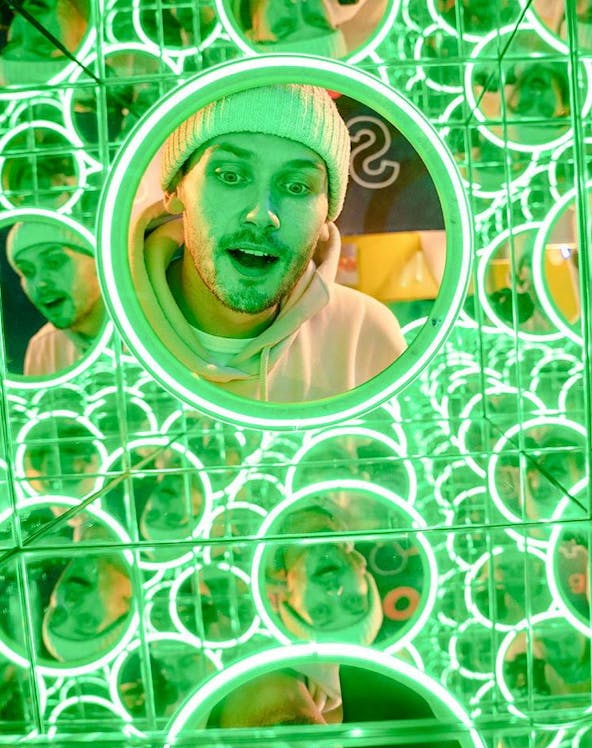 Man exploring mirror maze at World of Illusion exhibit.