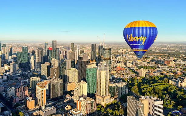 Hot air balloon over Melbourne skyline at sunrise.