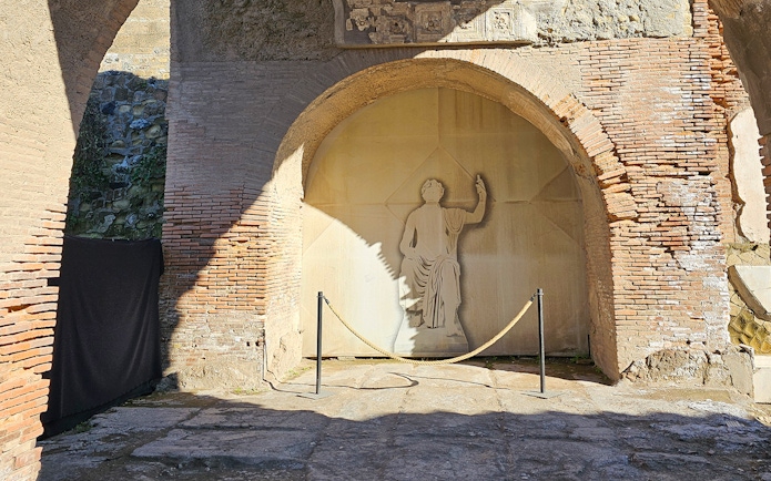 Herculaneum fresco depicting a figure in a toga on an ancient brick wall.