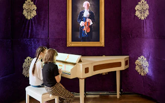 Children playing a harpsichord at Prague Mozart Interactive Museum.