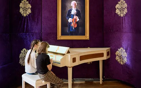 Children playing a harpsichord at Prague Mozart Interactive Museum.