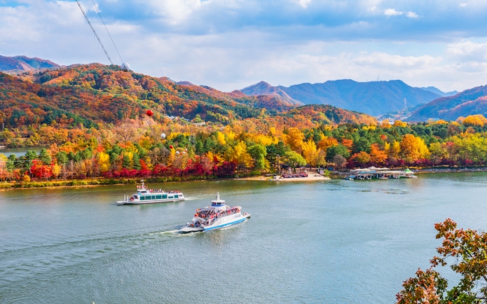 Ferry crossing to Nami Island with autumn foliage in the background, South Korea.