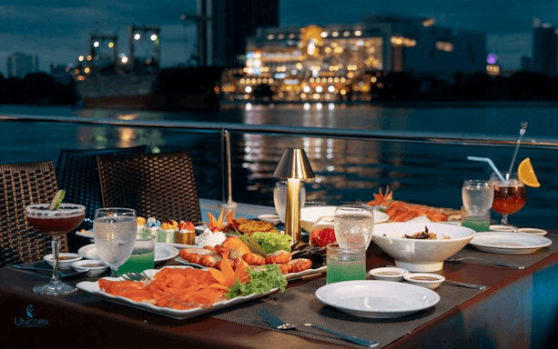 Dinner setup on a Bangkok river cruise with seafood and city lights in the background.