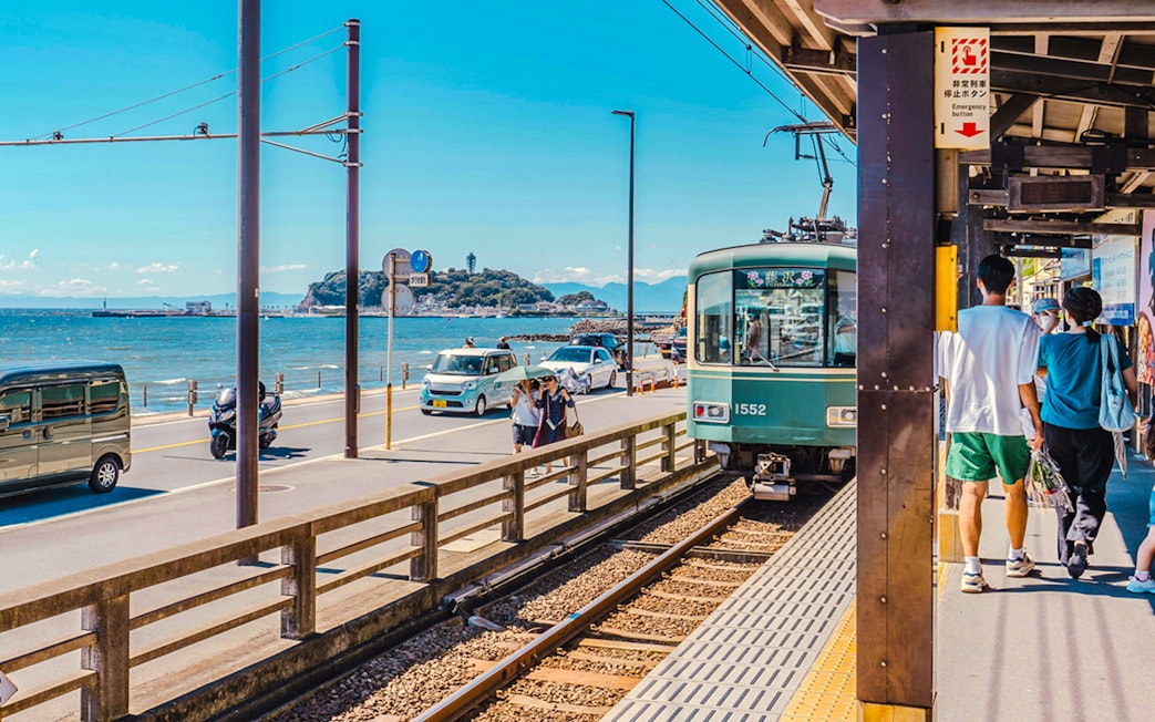 Train arriving at Kamakurakōkō-Mae Station with ocean view in Kamakura, Japan.