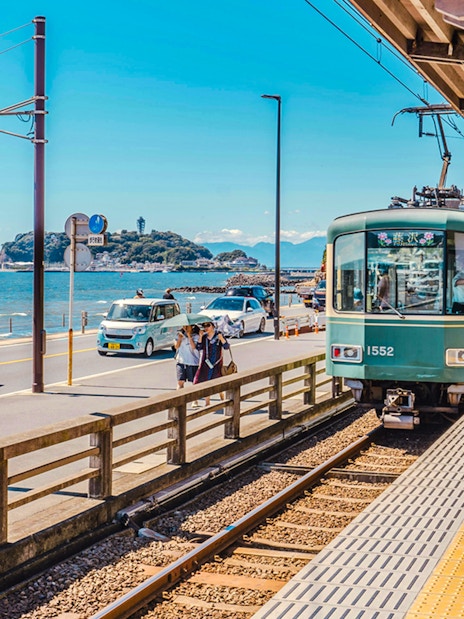 Train arriving at Kamakurakōkō-Mae Station with ocean view in Kamakura, Japan.
