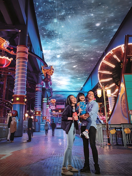 Family enjoying Genting Skytropolis Indoor Theme Park with vibrant lights and attractions.