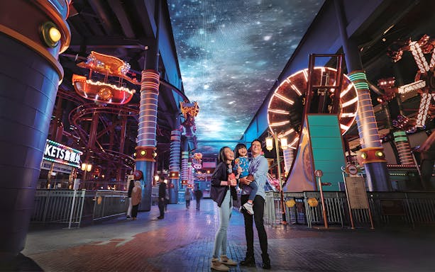 Family enjoying Genting Skytropolis Indoor Theme Park with vibrant lights and attractions.