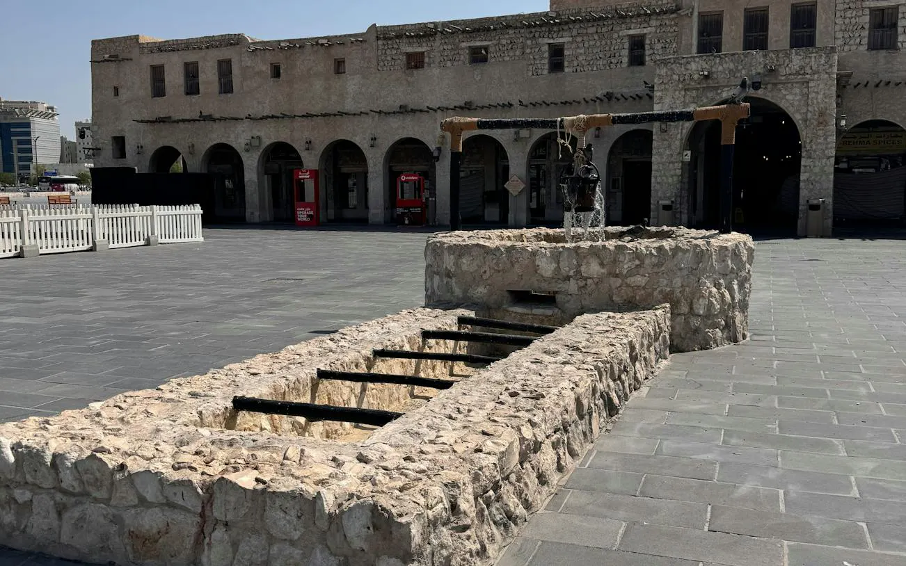 Historic stone well in Souq Waqif courtyard, Doha, part of self-guided city exploration game.