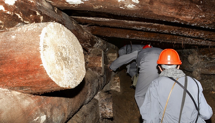 Männer mit orangenen Schutzhelmen und grauer Arbeitskleidung im Salzbergwerk Wieliczka