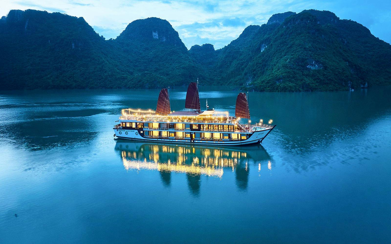 Aerial view of Amanda Luxury Cruise illuminated at night on tranquil waters.
