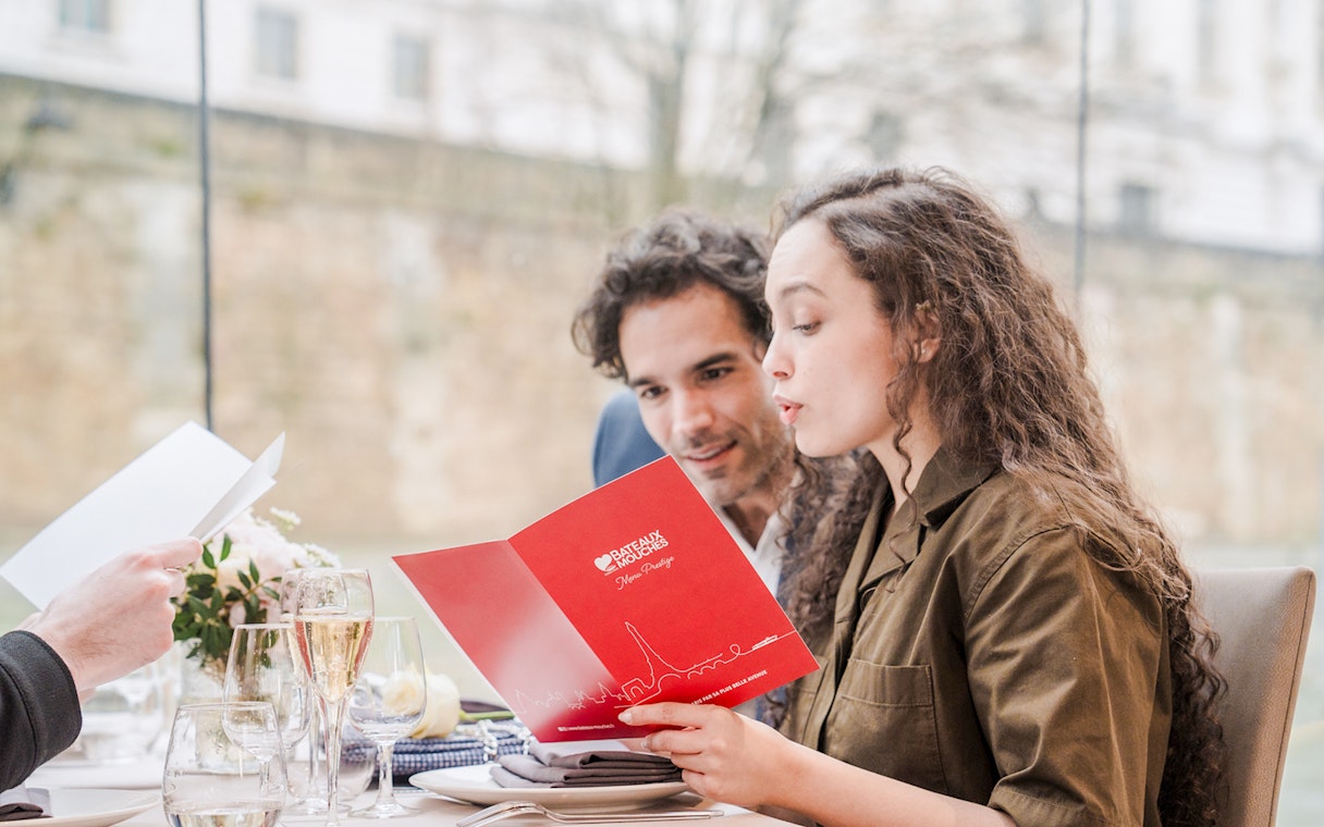 Couple reading menu on Seine River sightseeing lunch cruise in Paris.