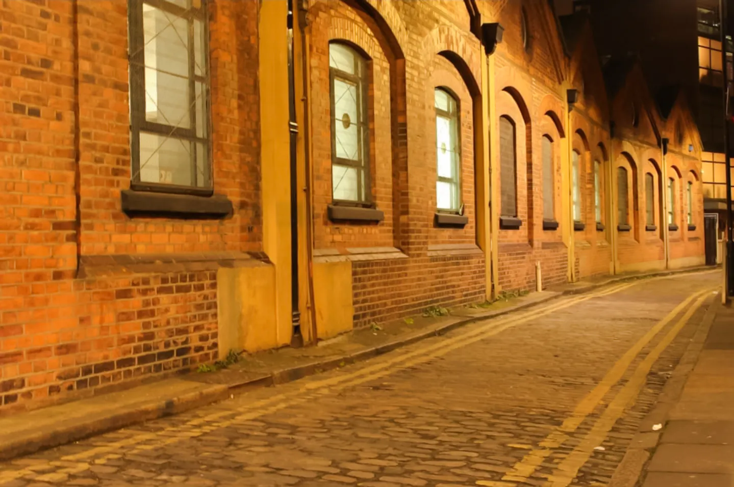 Narrow cobblestone street in London at night, part of Jack the Ripper tour.
