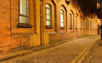 Narrow cobblestone street in London at night, part of Jack the Ripper tour.