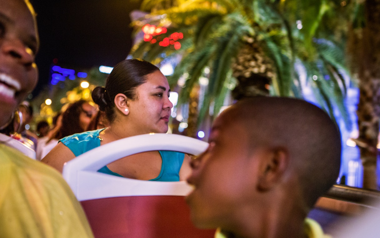 Tourists enjoying the Big Bus Dubai Night Tour with city lights and palm trees in the background.