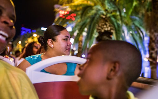 Tourists enjoying the Big Bus Dubai Night Tour with city lights and palm trees in the background.
