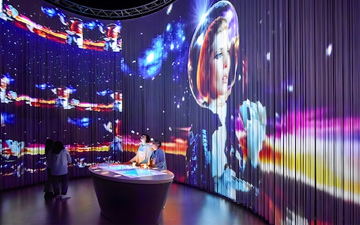 Visitors at Lavazza Museum in Turin viewing immersive space-themed exhibit.