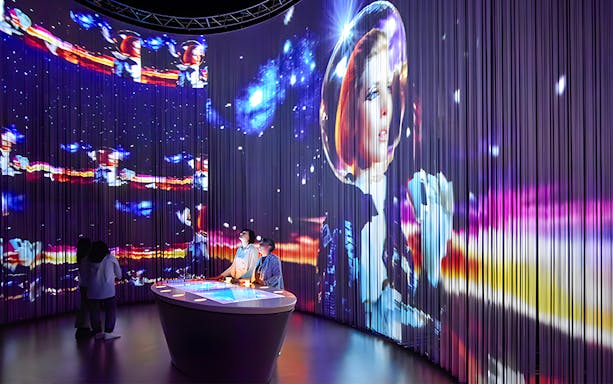 Visitors at Lavazza Museum in Turin viewing immersive space-themed exhibit.