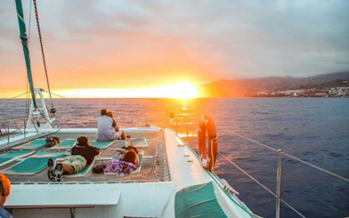 Catamaran at sunset in Madeira with passengers watching the ocean.