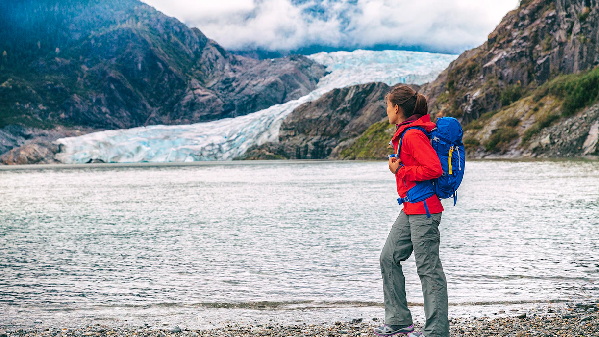 Traveler with backpack near Mendenhall Glacier in Juneau, Alaska.