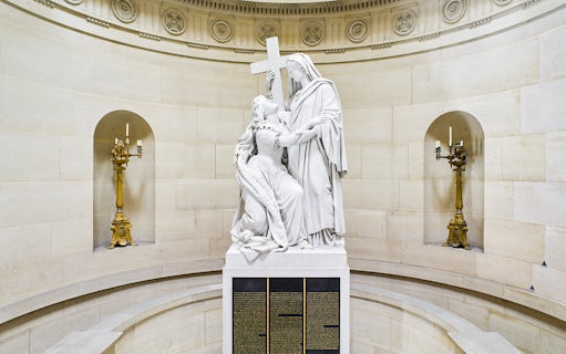 Statue inside Expiatory Chapel, Paris, depicting a kneeling figure holding a cross.