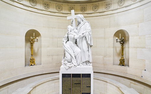 Statue inside Expiatory Chapel, Paris, depicting a kneeling figure holding a cross.