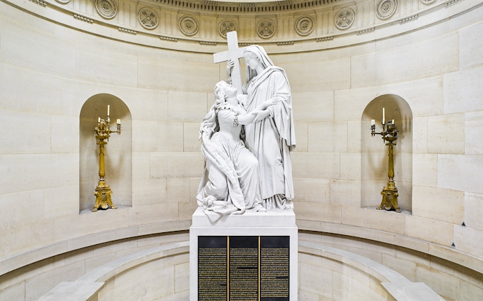 Statue inside Expiatory Chapel, Paris, depicting a kneeling figure holding a cross.