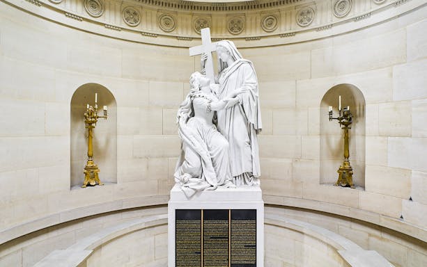 Statue inside Expiatory Chapel, Paris, depicting a kneeling figure holding a cross.