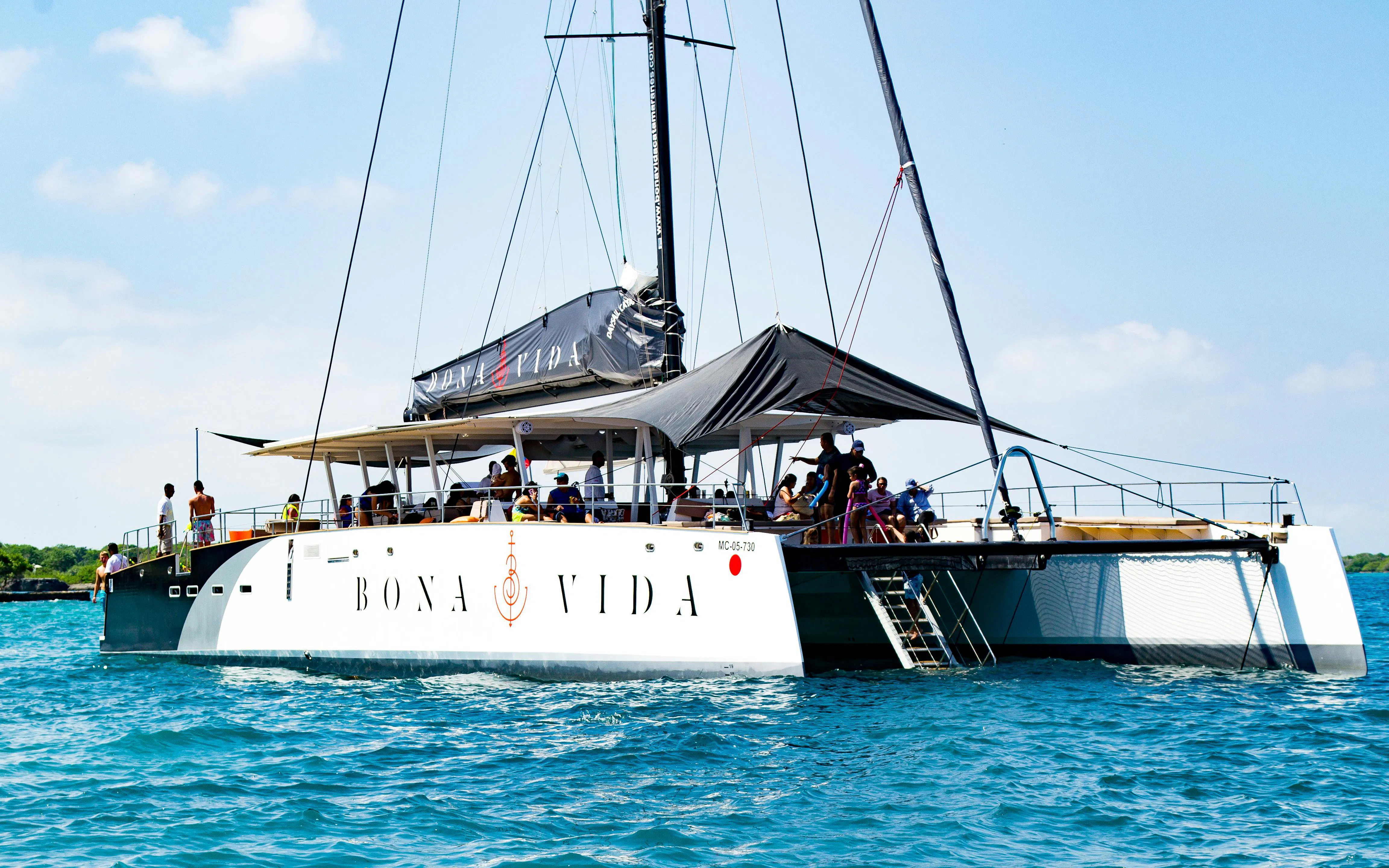 Catamaran with passengers on Rosario Islands cruise in clear blue water.