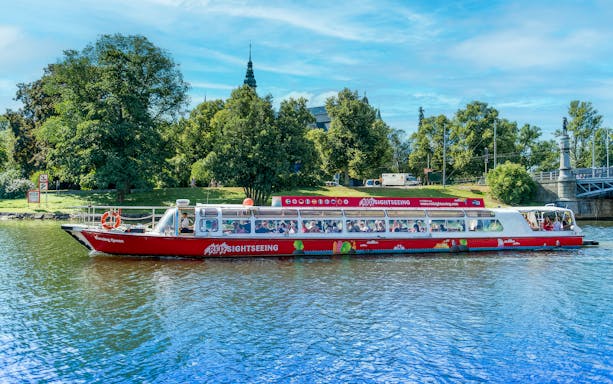 Sightseeing boat on a canal in Stockholm, Sweden with lush greenery in the background.