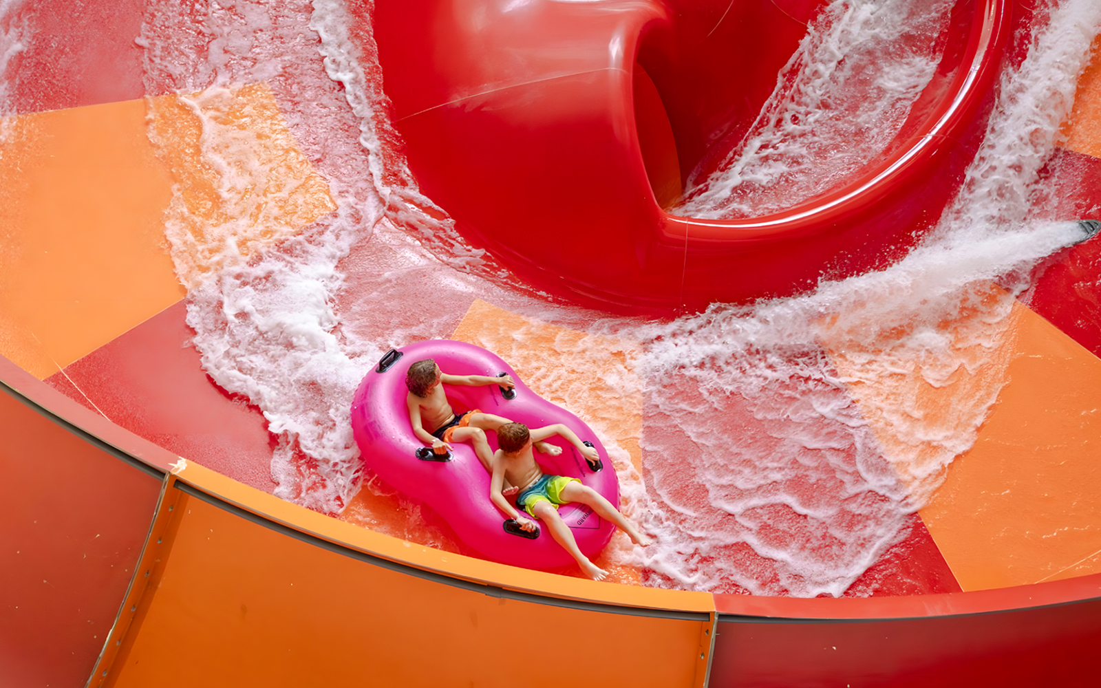 Two children on a pink raft ride the Lemur Leap water slide at Nickelodeon Universe, American Dream.