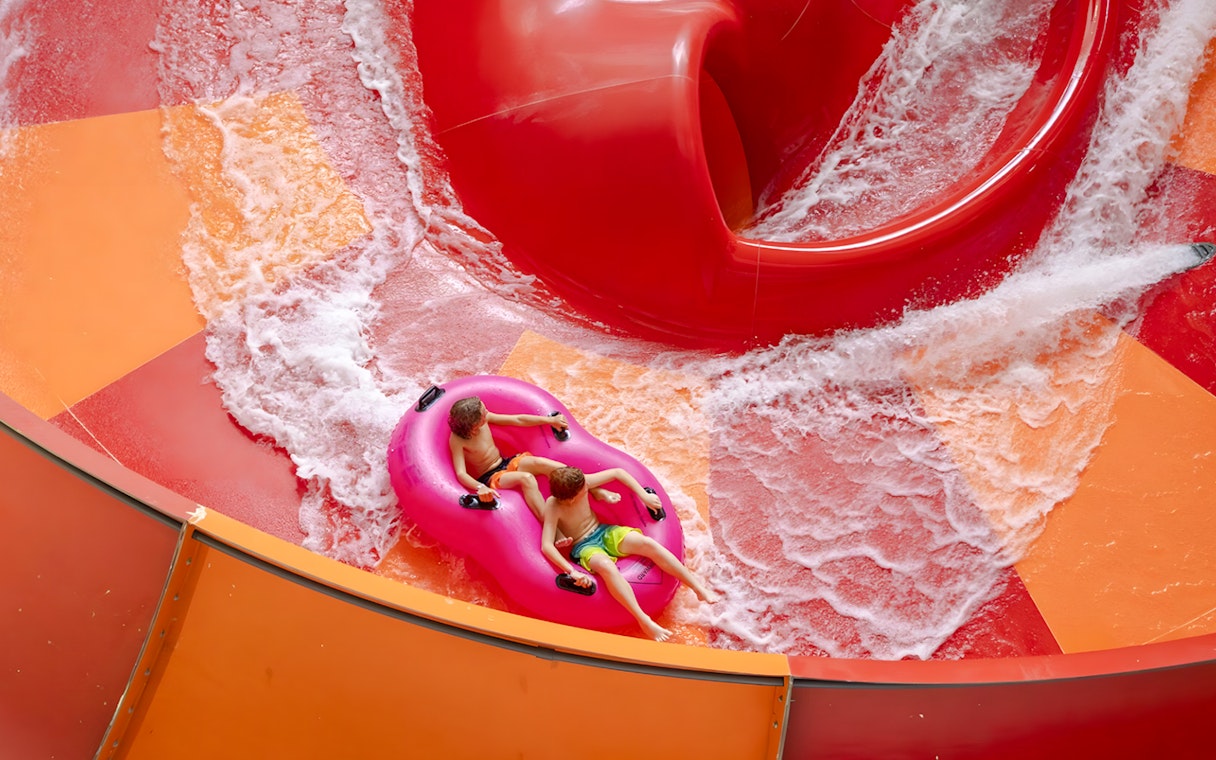 Two children on a pink raft ride the Lemur Leap water slide at Nickelodeon Universe, American Dream.