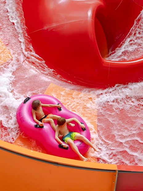 Two children on a pink raft ride the Lemur Leap water slide at Nickelodeon Universe, American Dream.