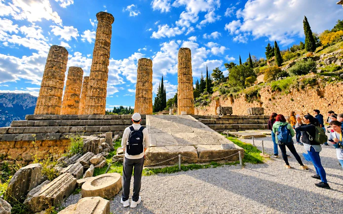 Visitors exploring ancient ruins at Delphi temple, Greece.
