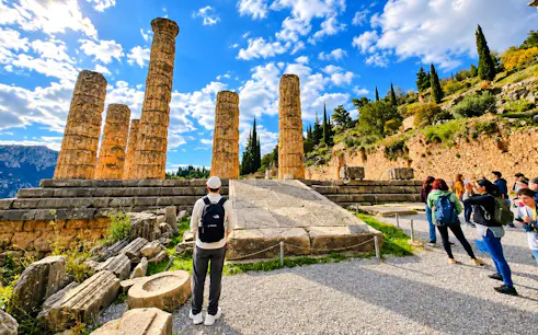 Visitors exploring ancient ruins at Delphi temple, Greece.