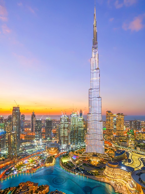 Burj Khalifa towering over Dubai skyline at sunset.