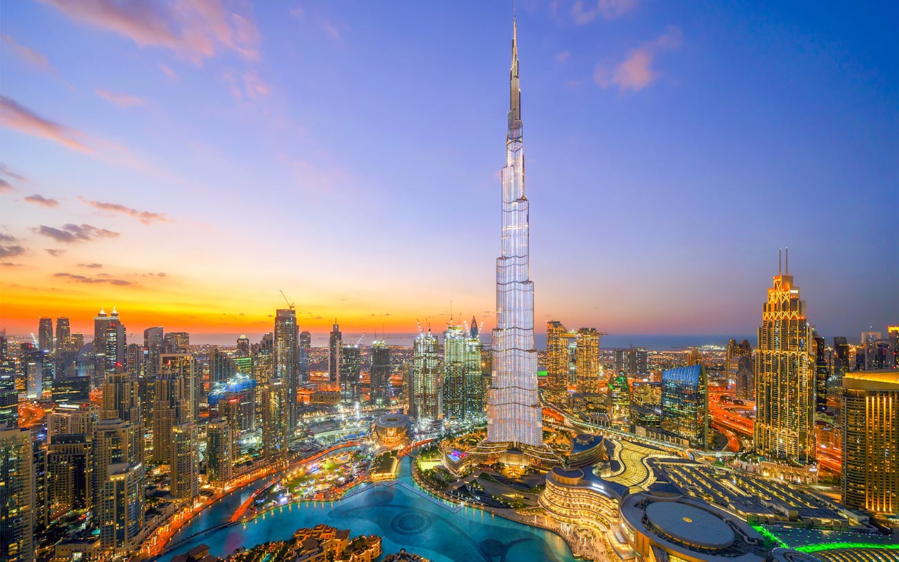 Burj Khalifa towering over Dubai skyline at sunset.