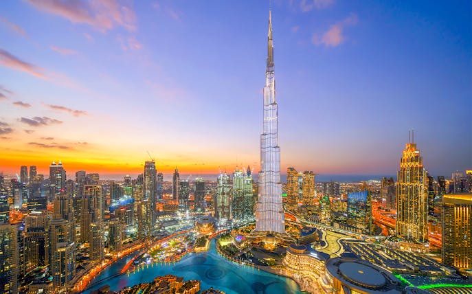 Burj Khalifa towering over Dubai skyline at sunset.