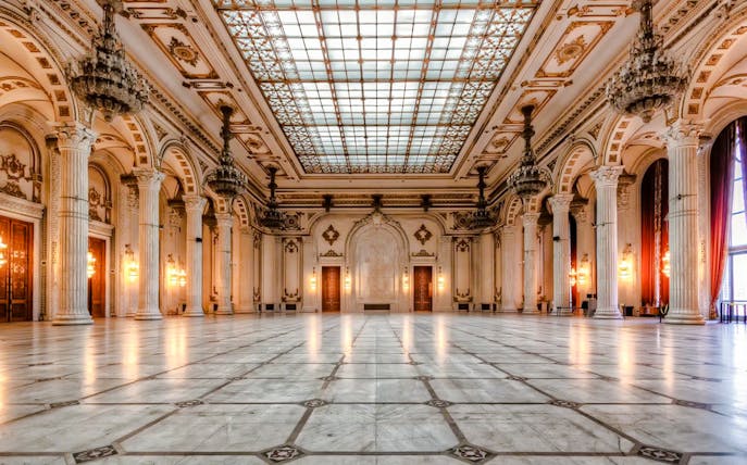 Interior of the Palace of Parliament in Bucharest with ornate columns and chandeliers.