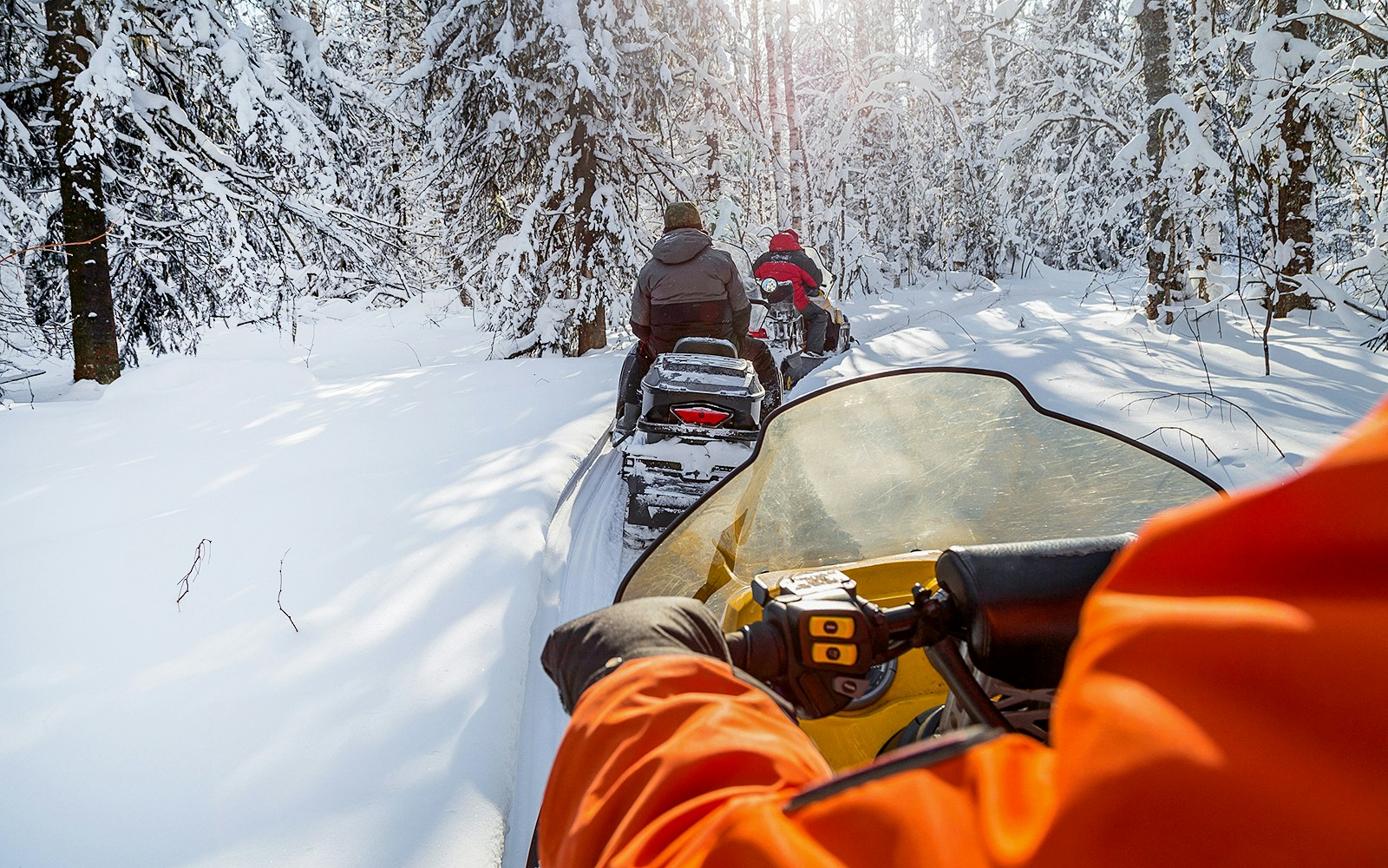 Snowmobiles driving through snowy forest in Zakopane.
