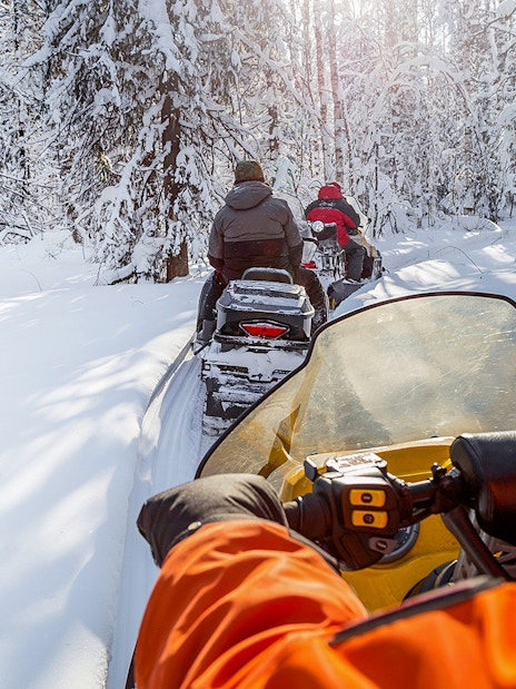 Snowmobiles driving through snowy forest in Zakopane.