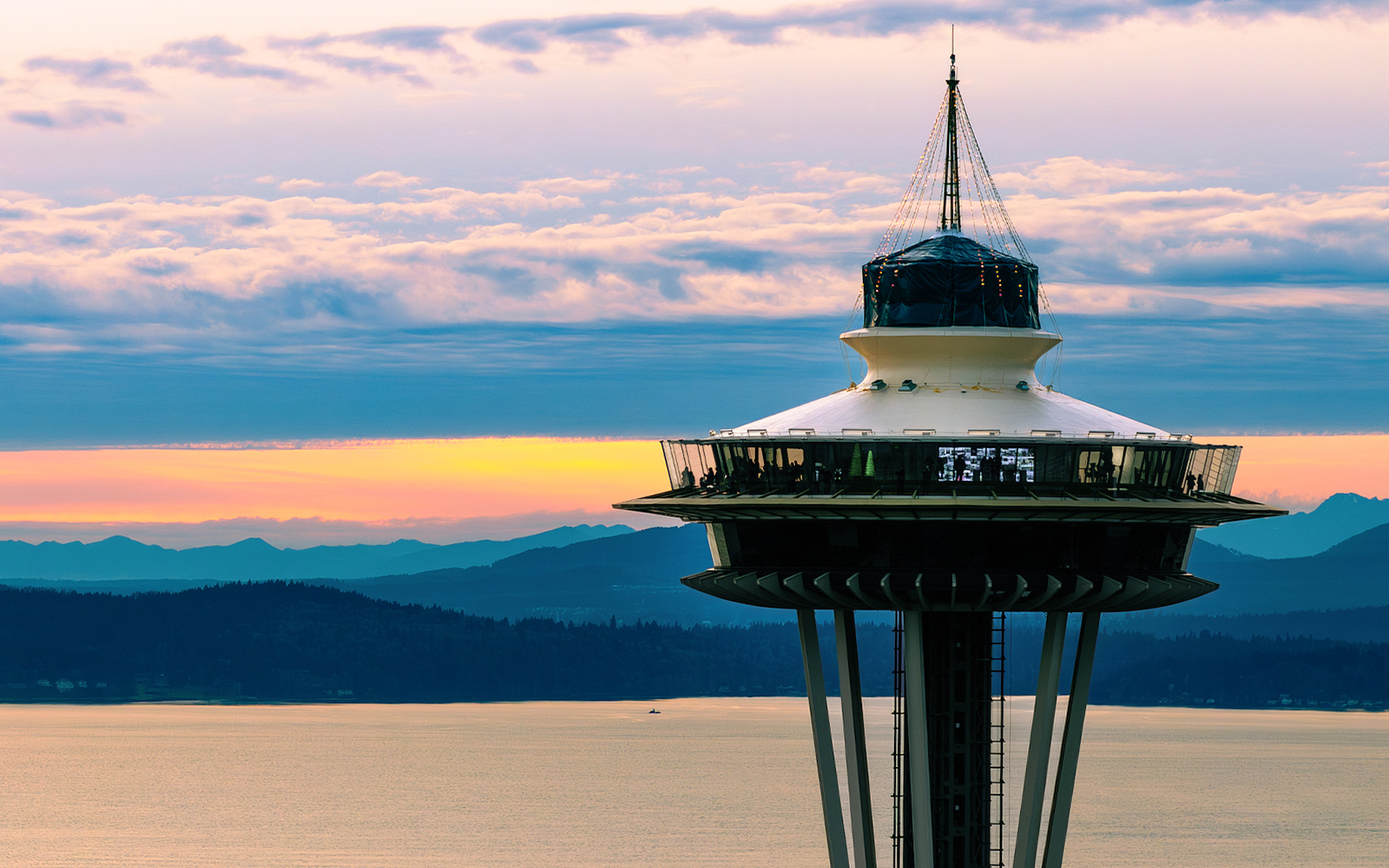 Seattle Space Needle close-up at sunset with mountains in the background.