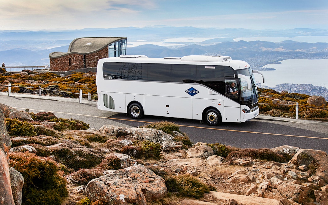 Tour bus on Mt Wellington road with scenic view of Hobart, Tasmania.
