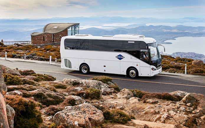 Tour bus on Mt Wellington road with scenic view of Hobart, Tasmania.